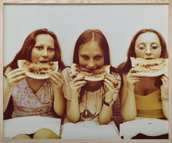 Fotografie von drei jungen Frauen, die in eine Scheibe Wassermelone beißen