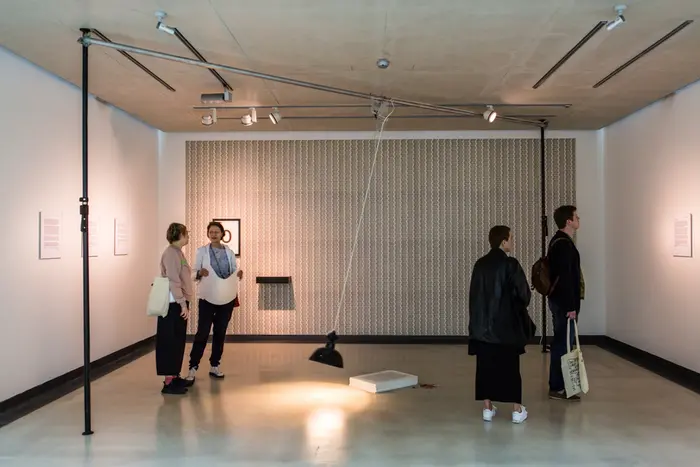 Vier Besucher*innen stehen in einem Ausstellungsraum