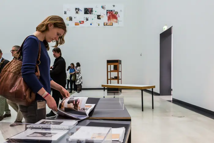 Eine Frau blättert in einem Ausstellungsraum einen Bildkatalog.