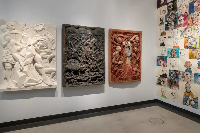 drei Reliefs in weiß, grau und rot hängen nebeneinander