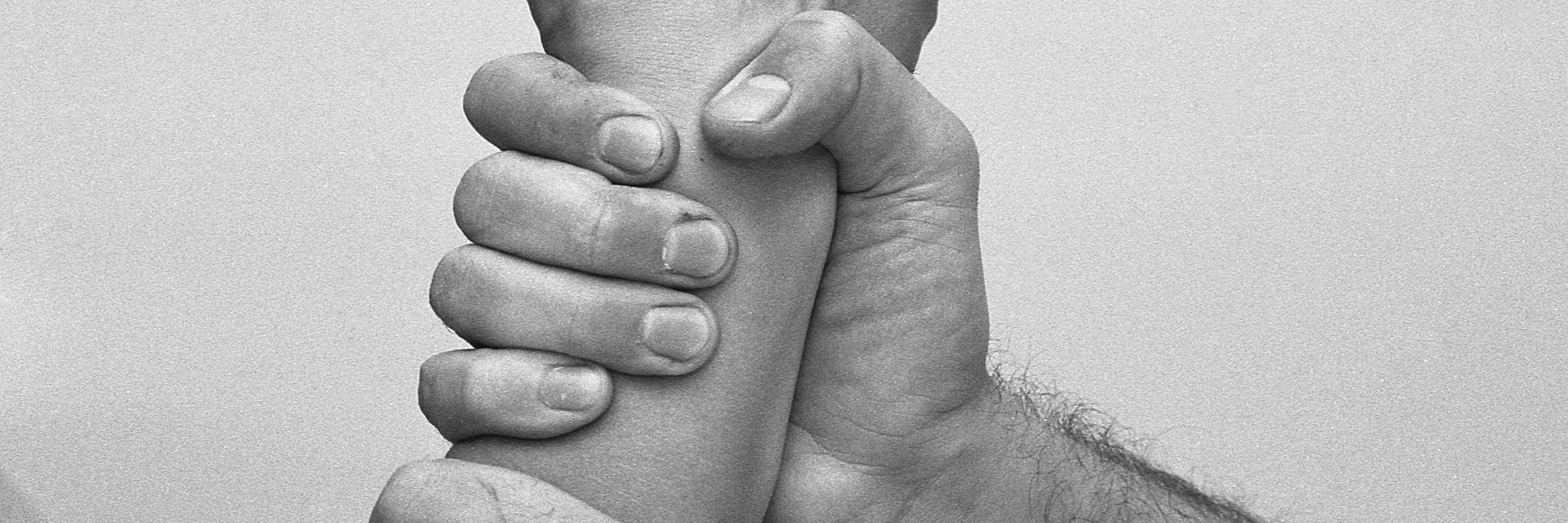 ein Unterarm, der von zwei Händen festgehalten wird
