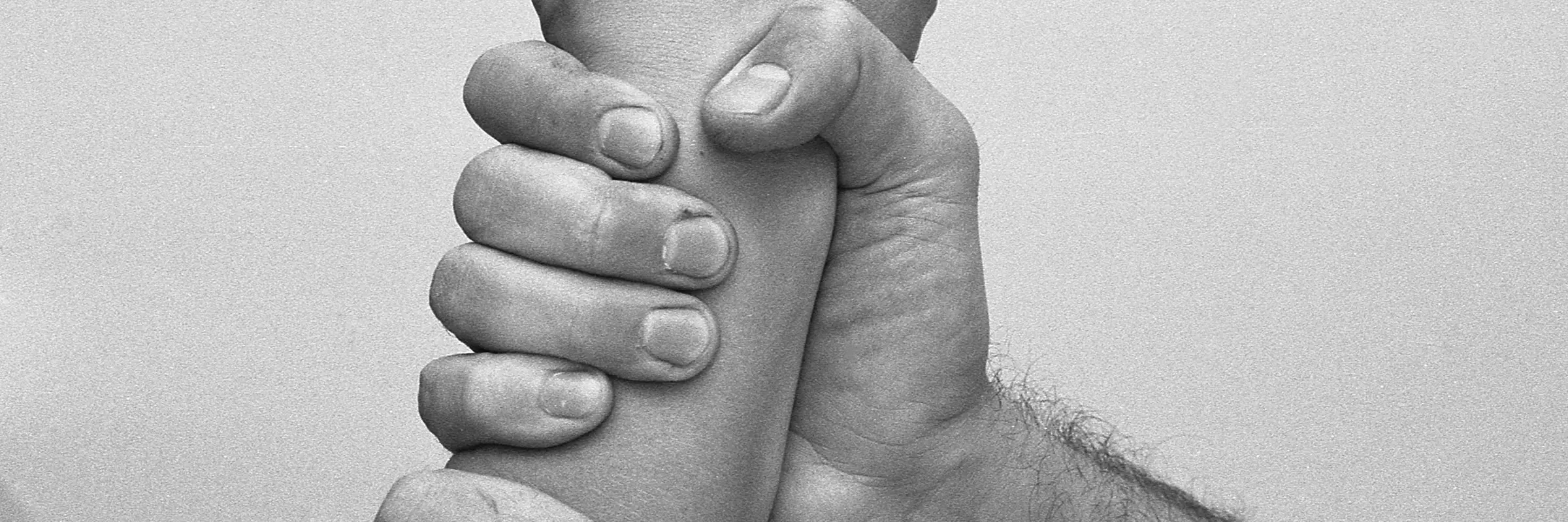 ein Unterarm, der von zwei Händen festgehalten wird