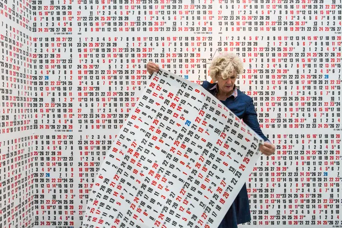 Eine Frau beklebt einen Raum mit Tapeten, auf denen Zahlen zu sehen sind. 