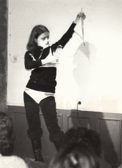 Schwarz-Weiß-Fotografie einer Frau, die sich rasiert und dabei Kleidung trägt.