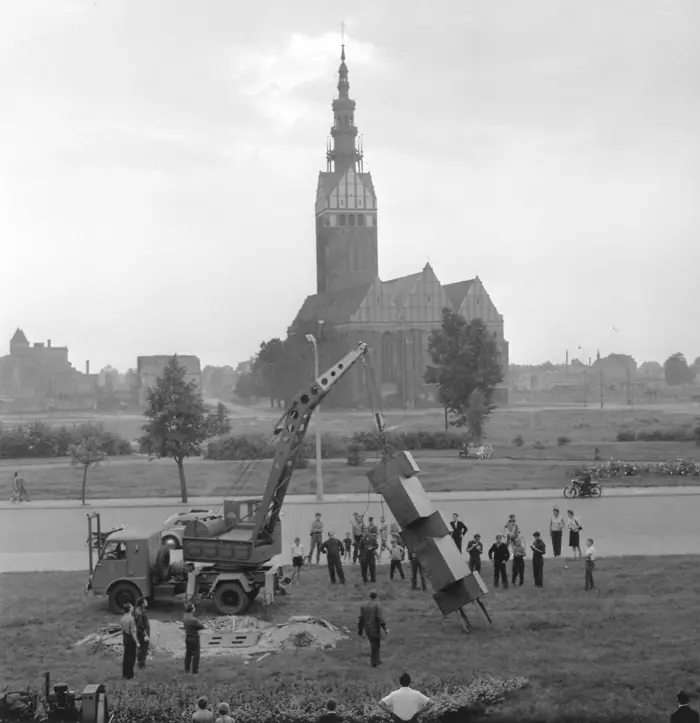 schwarzweiß Fotografie mit einer Kirchenreplik, die an einem Kran hängt