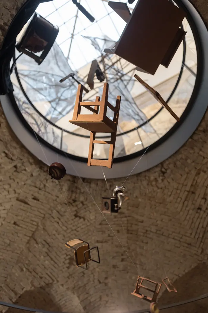 Ausstellungansicht "Alle Macht der Imagination!" Blick nach oben, es hängen Stühle von der Decke