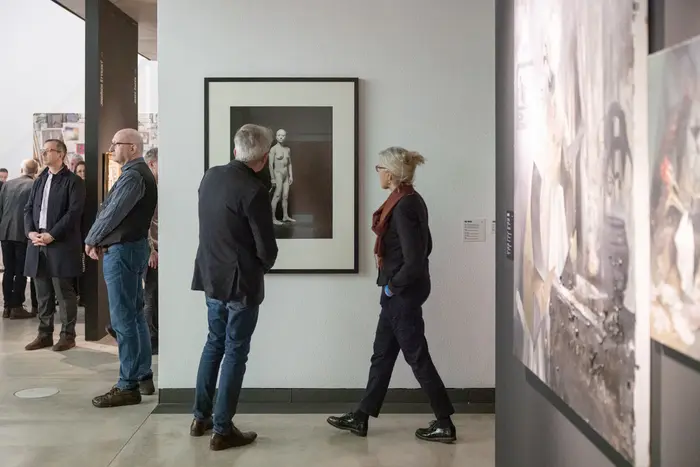 Ausstellungsansicht "Alle Macht der Imagination!" Menschen betrachten eine schwarz-weiß Fotografie in der Ausstellung